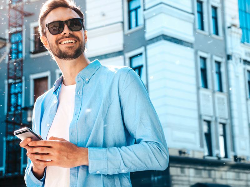 Ein Mann mit Brille, der sein Telefon in der Hand hält