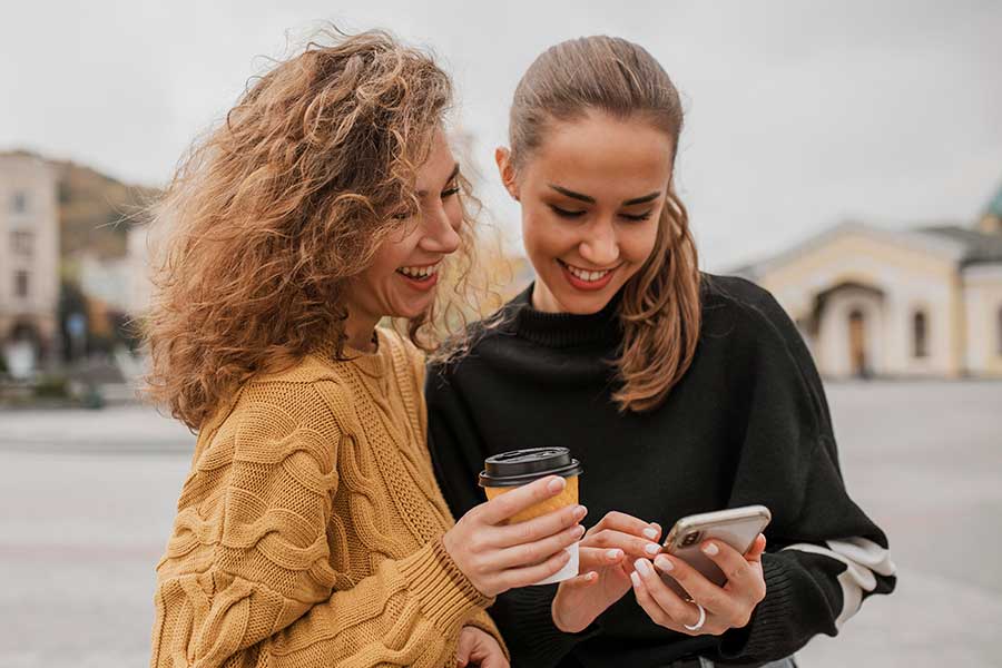 Zwei Frauen, die eine Antwort per SMS schicken.