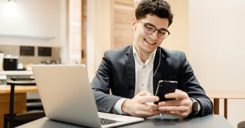 Ein lächelnder Selbstständiger, der sein Telefon in der Hand hält und sich auf sein Gespräch vorbereitet.